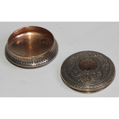 855 - A 19th century silver and gold coloured metal circular snuff box, chased overall in the Indian taste... 