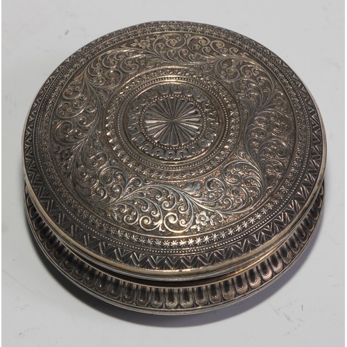 855 - A 19th century silver and gold coloured metal circular snuff box, chased overall in the Indian taste... 