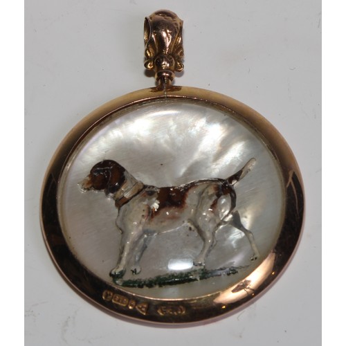 1503 - An early 20th century 9ct gold mounted rock crystal pendant, carved and painted with a dog, on a mot... 