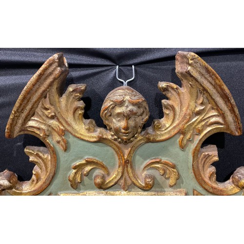 2437 - A Baroque parcel-gilt and painted looking glass, the break-arch pediment centred by a mask, carved l... 