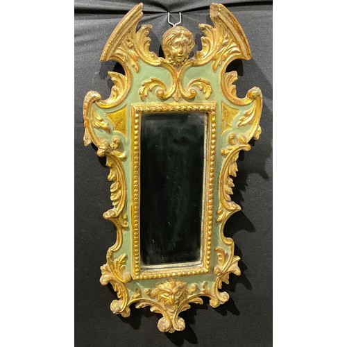 2437 - A Baroque parcel-gilt and painted looking glass, the break-arch pediment centred by a mask, carved l... 