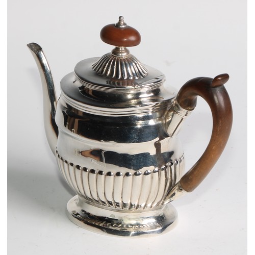 924 - A George III silver half-fluted bachelor's teapot, hinged cover, scroll-capped handle, skirted base,... 