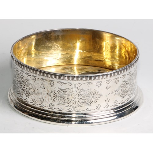 1111 - A Victorian silver wine coaster, the gallery and gilt interior engraved with leafy strapwork, egg-an... 