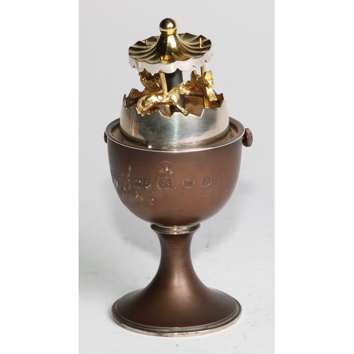 1198 - Anthony Gordon Elson (Bn.1935)	- an Elizabeth II silver surprise egg, enclosing a gilt carousel, 11c... 