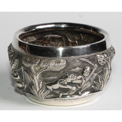 860 - A Burmese silver circular bowl, repousse chased with hunting scenes, the base with a bird in a tree,... 