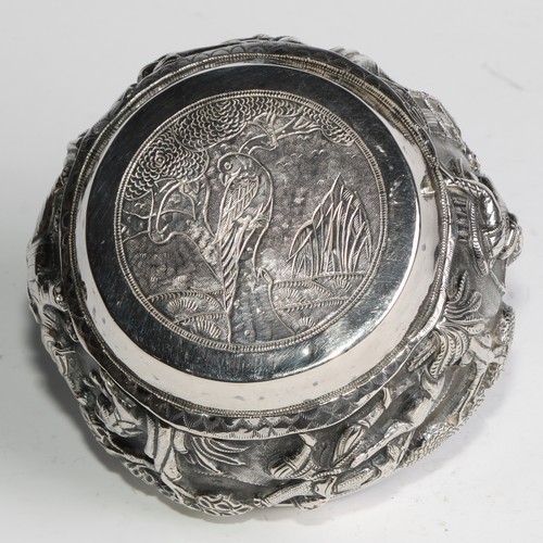 860 - A Burmese silver circular bowl, repousse chased with hunting scenes, the base with a bird in a tree,... 