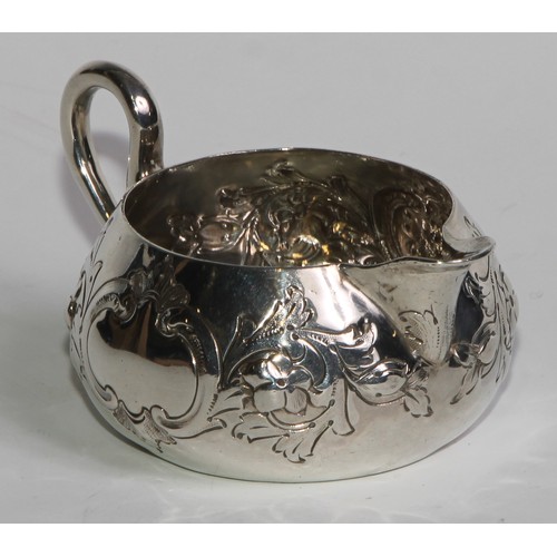 1088 - A Victorian silver cream jug, chased with flowers, stiff leaves and C-scrolls, 9cm long, Horace Wood... 