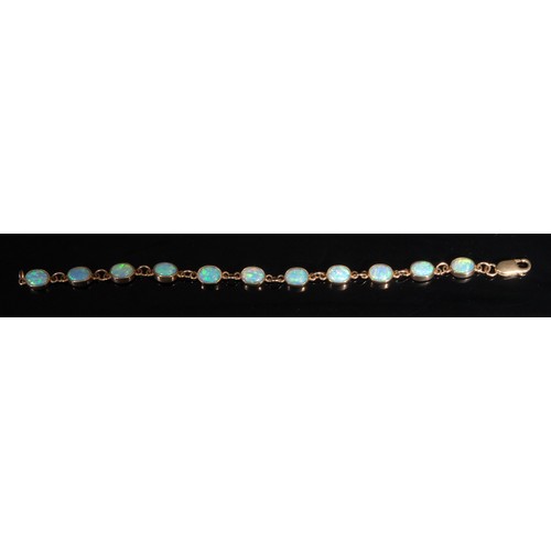 1324 - A 9ct gold and opal bracelet, 11 bezel set cabochon stones, play of colour in blue and green, 19cm l... 