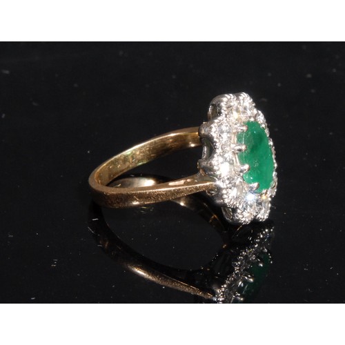 1359 - A diamond and emerald cluster ring, the central oval facet cut raised claw set emerald within 10 cir... 