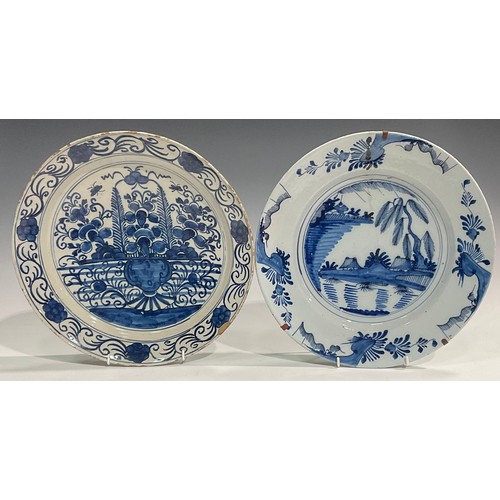 310 - A set of three Delftware chargers, boldly decorated in underglaze blue with flowers, 30.5cm diameter... 