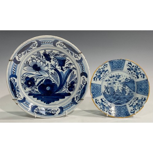 310 - A set of three Delftware chargers, boldly decorated in underglaze blue with flowers, 30.5cm diameter... 