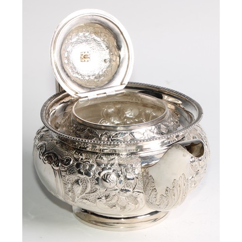 908 - A George III Irish silver teapot, chased with chased with flowers and stiff leaves on a scale ground... 