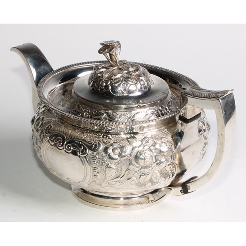 908 - A George III Irish silver teapot, chased with chased with flowers and stiff leaves on a scale ground... 