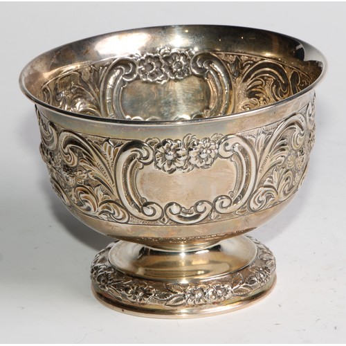 1037 - A pair of Victorian silver pedestal bowls, chased with flowers and scrolling leaves, centred by vaca... 