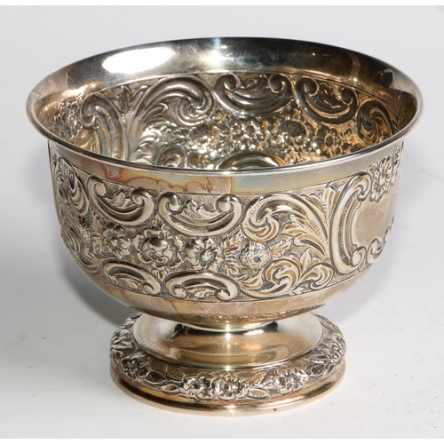 1037 - A pair of Victorian silver pedestal bowls, chased with flowers and scrolling leaves, centred by vaca... 