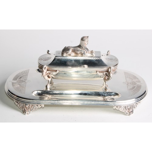 846 - An Egyptian Revival E.P.N.S inkstand, the cover crested by a sphinx, enclosing a pair of wells, the ... 