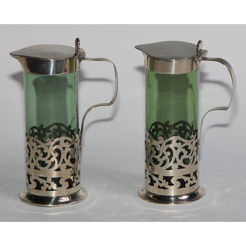 1018 - A pair of Edwardian silver mounted green glass liqueur jugs, hinged covers with anthemion thumb piec... 