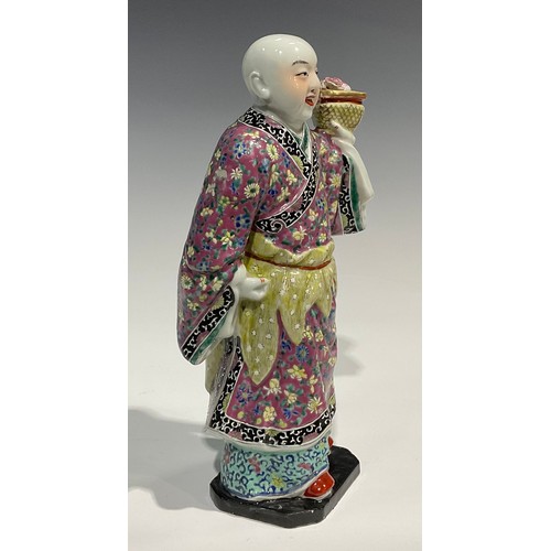 367 - A Chinese figure, of a girl holding a basket of flowers, brightly decorated in polychrome enamels, 3... 