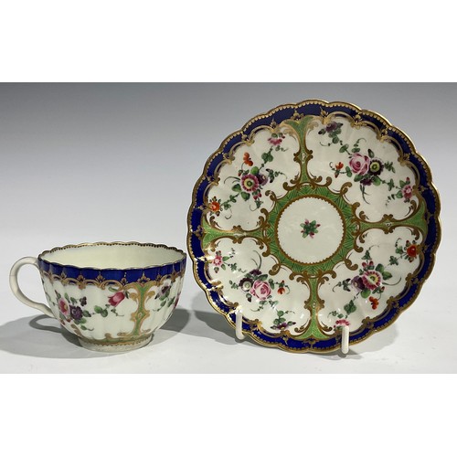 212 - A Worcester fluted teacup and saucer, painted with panels of colourful flowers on a green ground, bl... 