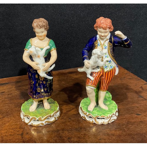 246 - A pair of Derby figures, of a boy and girl, he stands wearing a blue jacket and striped breeches hol... 