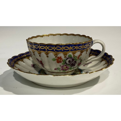 211 - A Worcester fluted teacup and saucer, circular cartouches painted with lakeside scenes, edged with a... 