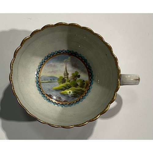 211 - A Worcester fluted teacup and saucer, circular cartouches painted with lakeside scenes, edged with a... 