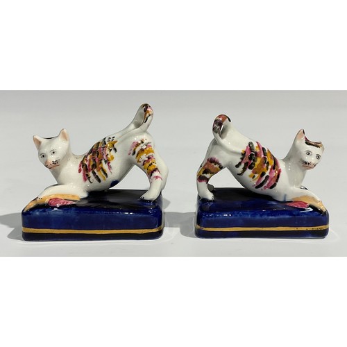 332 - A pair of Staffordshire cats, each trapping a bird under paw, painted in dappled tones of brown, bla... 