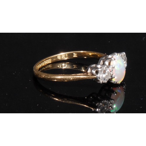 1482 - An 18ct gold opal and diamond ring, the central oval opal cabochon claw set in platinum, flanked by ... 