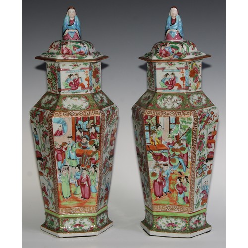 455 - A pair of Chinese famille rose hexagonal vases and covers, painted in the typical Cantonese manner w... 