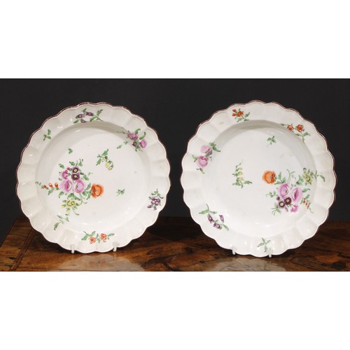 186 - A pair of Worcester shaped circular plates, painted in polychrome with scattered flowers, brown line... 