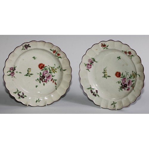 186 - A pair of Worcester shaped circular plates, painted in polychrome with scattered flowers, brown line... 