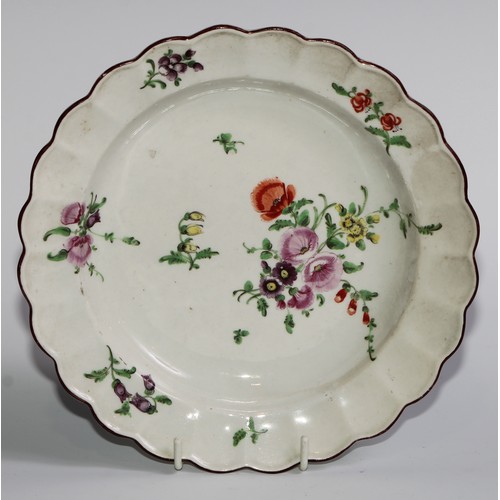 186 - A pair of Worcester shaped circular plates, painted in polychrome with scattered flowers, brown line... 