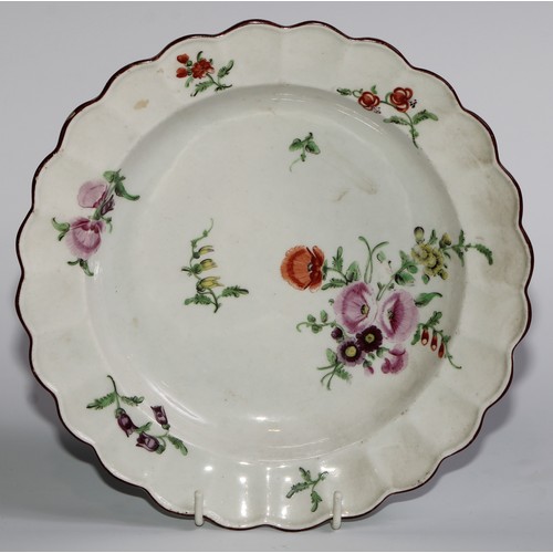 186 - A pair of Worcester shaped circular plates, painted in polychrome with scattered flowers, brown line... 