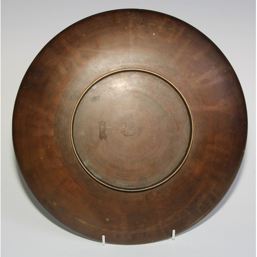 418 - A Japanese gilt and brown patinated bronze circular charger, applied with a bird on a blossoming pru... 