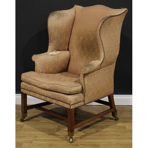 2045 - A George III wing chair, stuffed-over upholstery, squab cushion, internally chamfered legs, brass ca... 