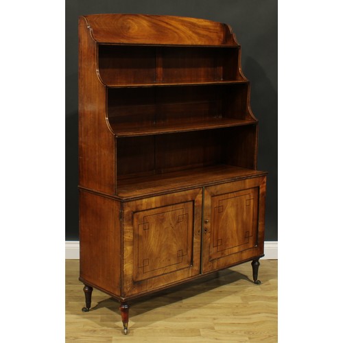 2364 - A Regency mahogany waterfall bookcase, open shelves above a pair of panel doors, turned feet, brass ... 