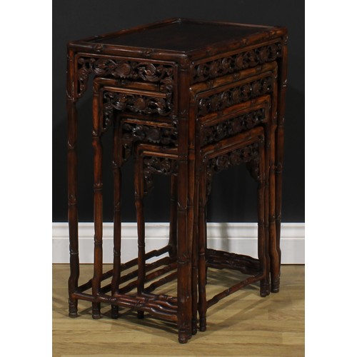 2372 - A set of Chinese hardwood quartetto tables, each apron pierced and carved with bats and shòu, the fr... 