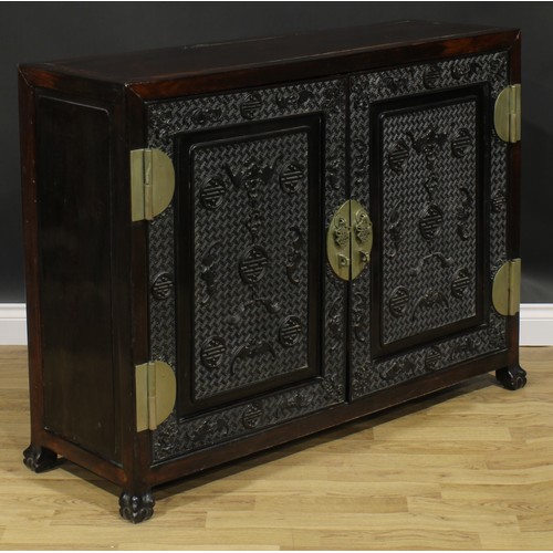 2030 - A Chinese hardwood side cabinet, rectangular top above a pair of panel doors carved and applied with... 