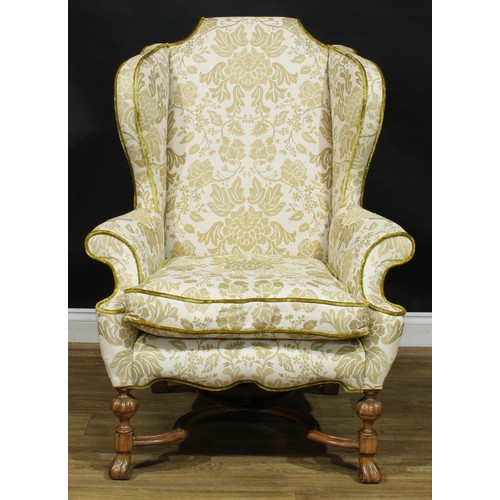 2180 - A William & Mary Revival wing chair, stuffed-over upholstery, squab cushion, shaped stretcher, Spani... 