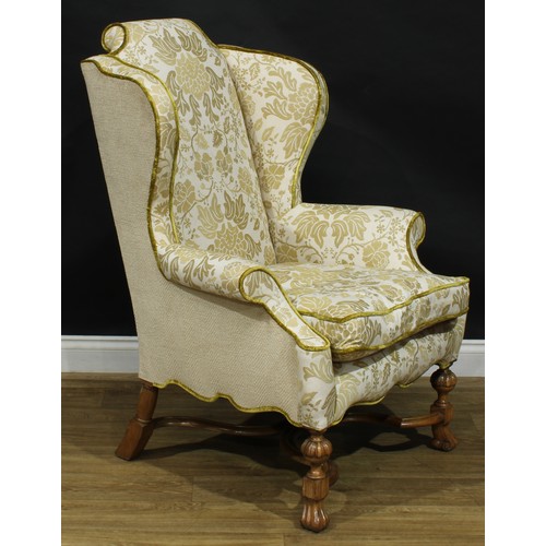 2180 - A William & Mary Revival wing chair, stuffed-over upholstery, squab cushion, shaped stretcher, Spani... 