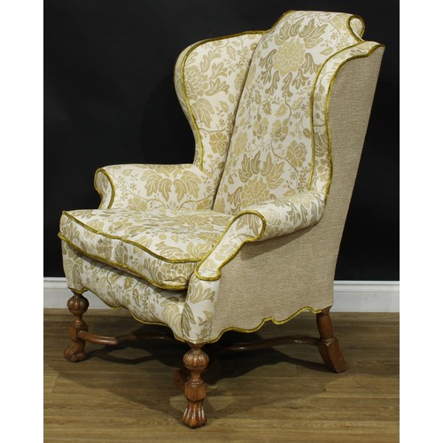 2180 - A William & Mary Revival wing chair, stuffed-over upholstery, squab cushion, shaped stretcher, Spani... 