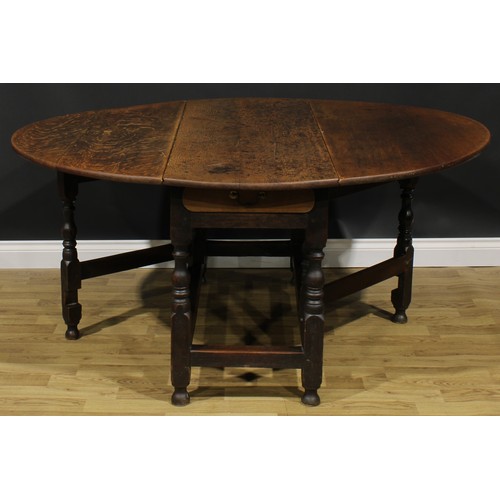 2001 - An 18th century oak gateleg dining table, oval top with fall leaves above a later frieze drawer, tur... 