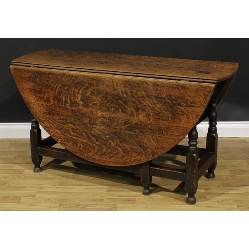 2001 - An 18th century oak gateleg dining table, oval top with fall leaves above a later frieze drawer, tur... 