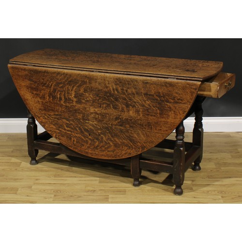 2001 - An 18th century oak gateleg dining table, oval top with fall leaves above a later frieze drawer, tur... 