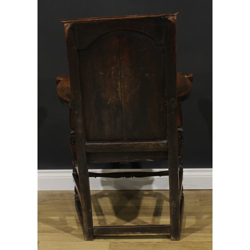 1998 - An 18th century oak and elm panel back armchair, rectangular back, shaped arms, plank seat, shaped a... 