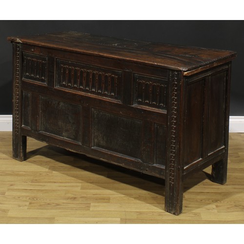 2157 - A late 17th century oak blanket chest, hinged top above a nulled panel front, the stiles carved with... 