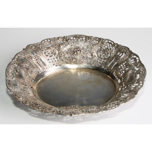 985 - A German silver shaped oval basket, pierced and embossed with flowers, leafy scrolls and vacant cart... 