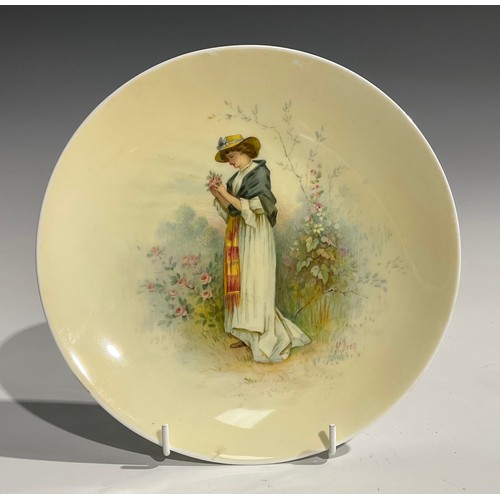 126 - A Minton circular plate, painted by J. E. Dean, with lady picking roses in a garden, lemon ground, s... 