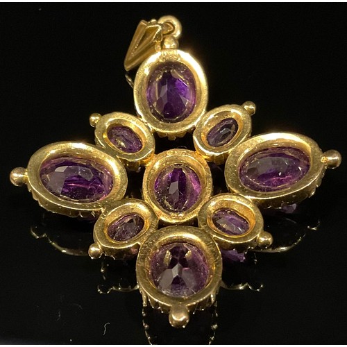 1322 - A 9ct gold and amethyst cruciform pendant, set with nine graduated oval cut stones, 4.5cm over loop