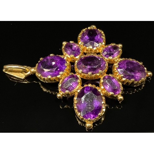 1322 - A 9ct gold and amethyst cruciform pendant, set with nine graduated oval cut stones, 4.5cm over loop